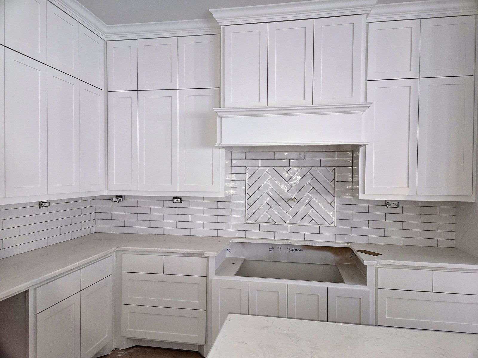 White shaker kitchen cabinets with subway tile and a herringbone accent